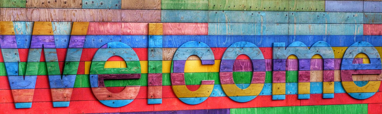 A sign reading welcome made of multi-coloured wood planks