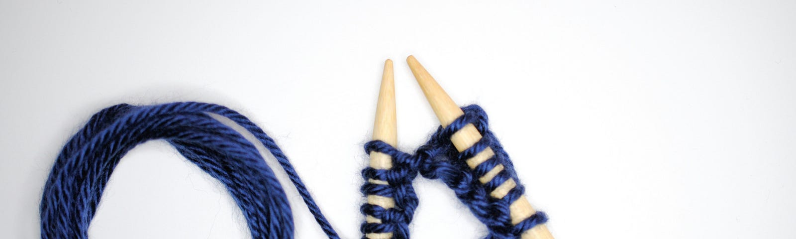 knitting with blue yarn and ivory needles