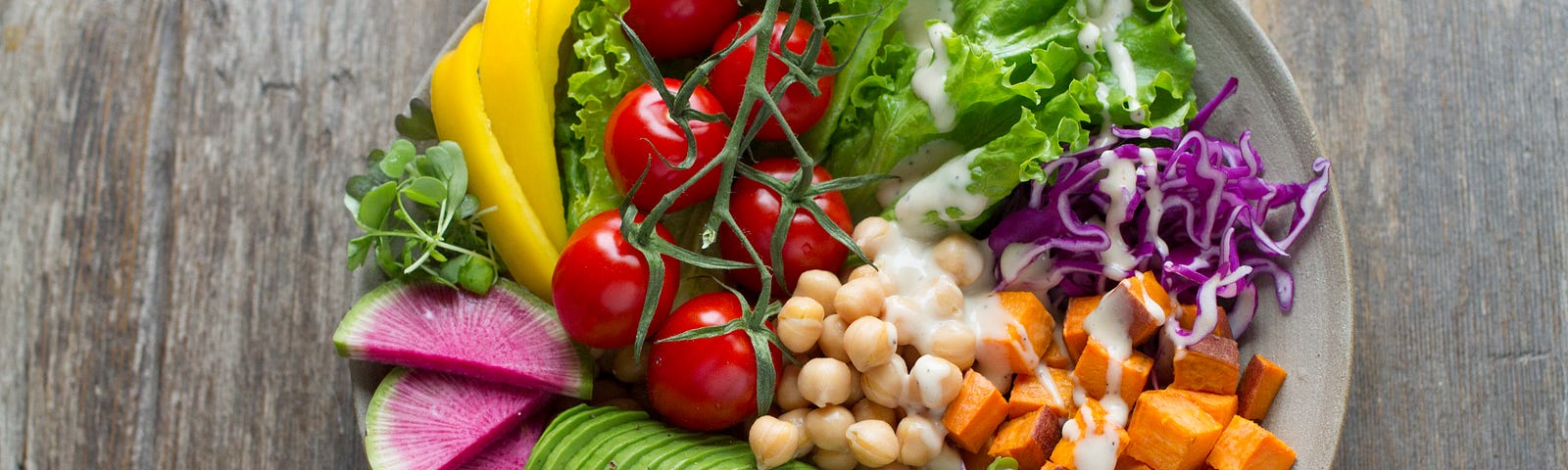 A bowl of fresh fruits, vegetables and cheese.