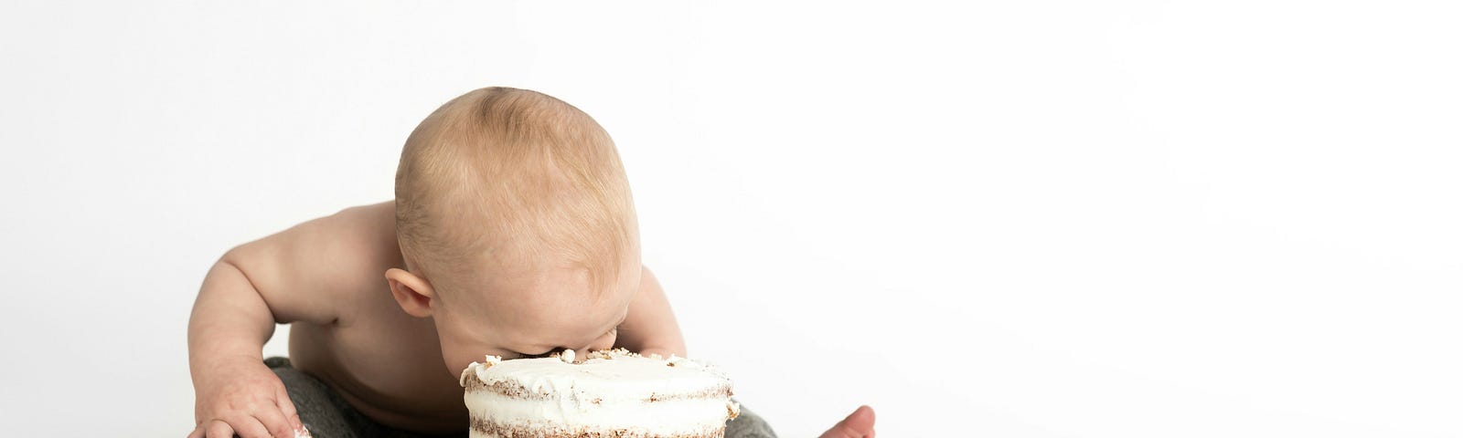 A baby plunges its face into a cake