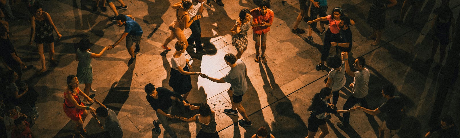 A dimly-lit dancefloor. Several couples are dancing the samba.