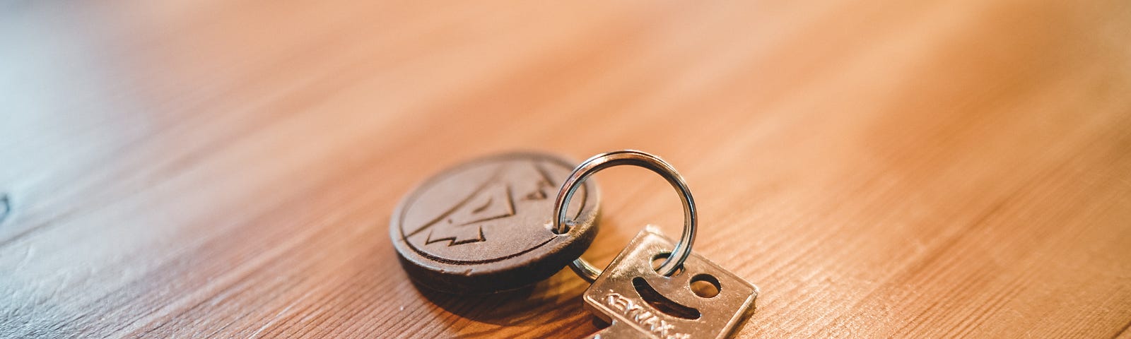 single key with smiley face lying on wooden table; key to freedom