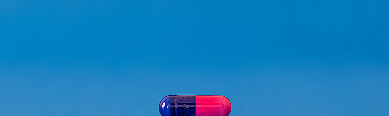 Blue and pink capsule sits against a medium blue background.