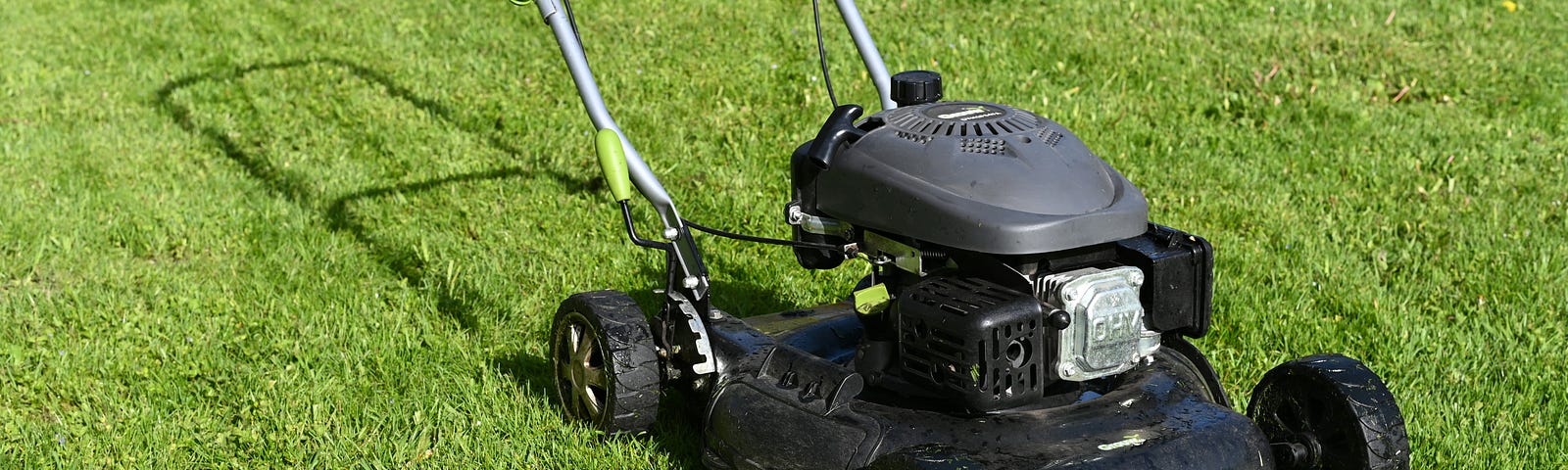 Black lawnmower, with a gas-powered engine, on a green lawn