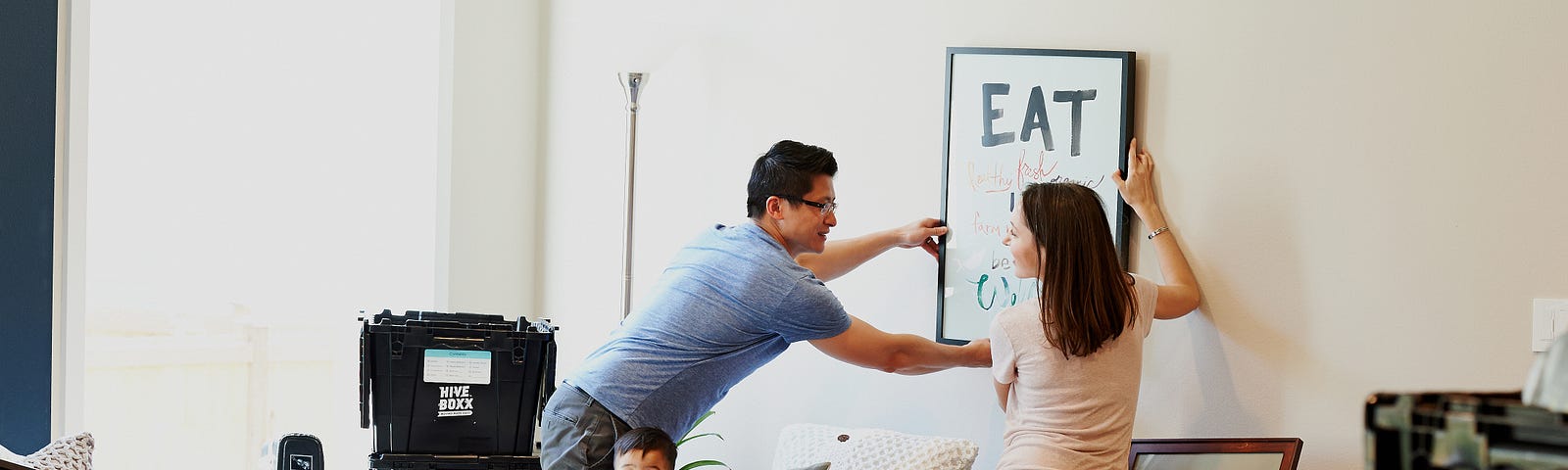 A young man helping a woman hang a picture in her new apartment as she is moving in.