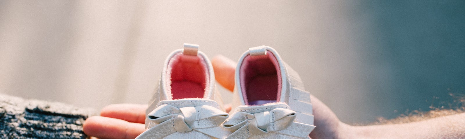 Baby shoes held in a couple’s hands. Focus on shoes.