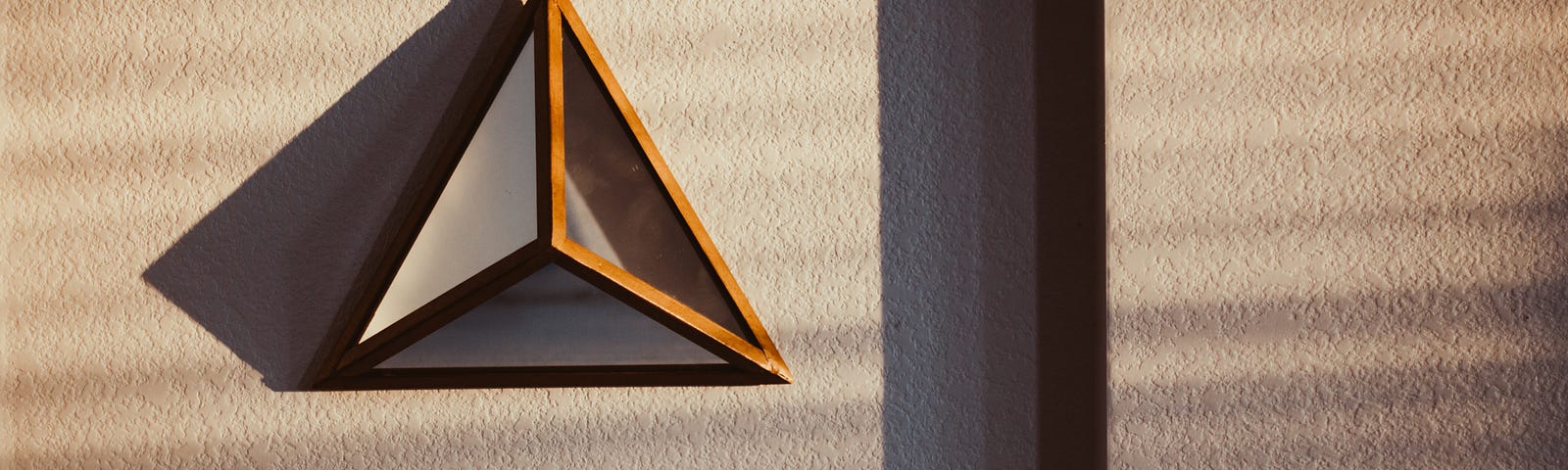 Image of a framed glass pyramid casting shadows on a textured background