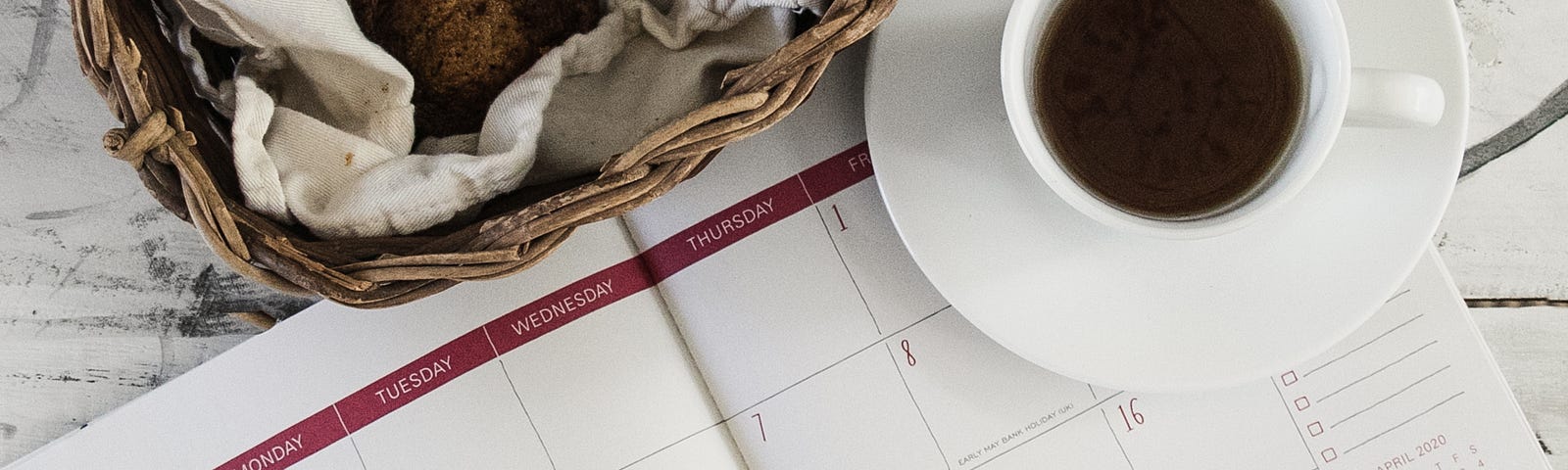 Image of open calendar book with coffee cup on the corner of it.