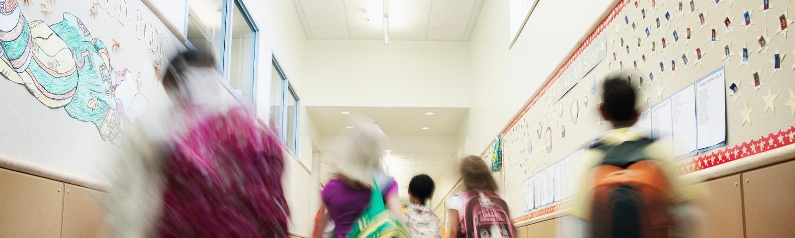 School hallway with blurred students walking away from the camera. Photo by Thomas Barwick/Getty Images