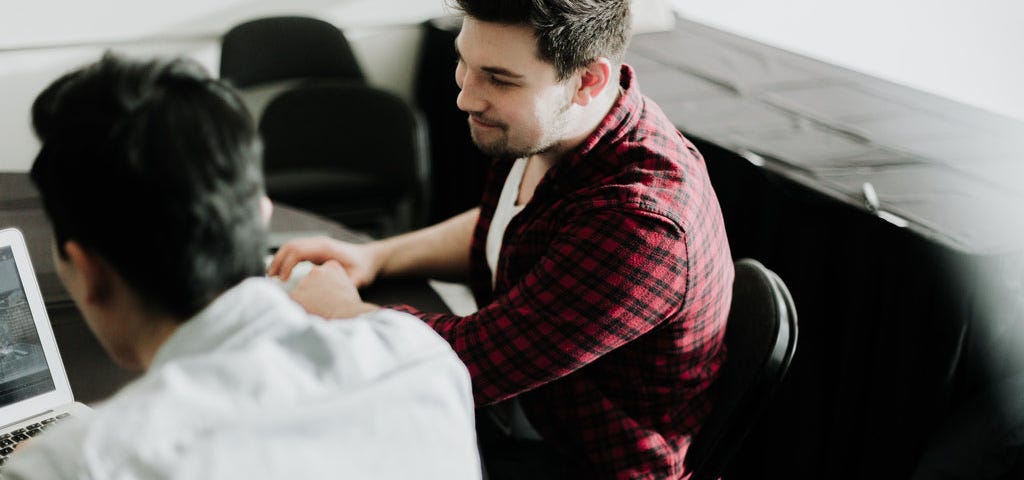 two men working together on a laptop