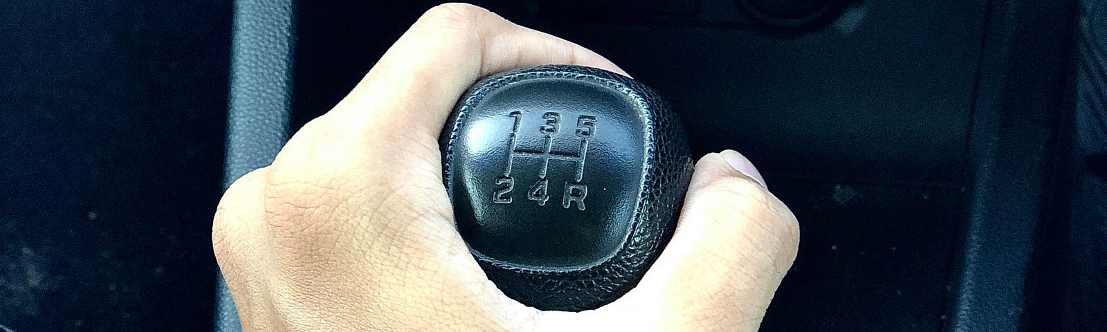 A man hand, holding a car gear.