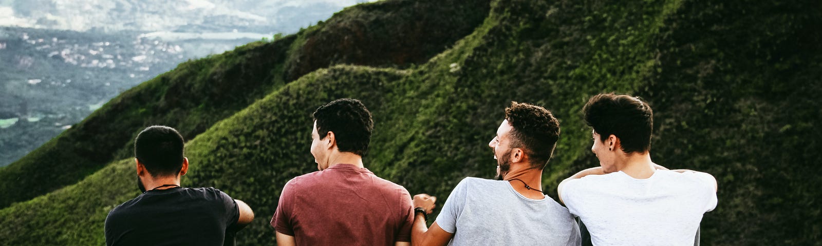 male friends sitting together and laughing on a rock — deep friendships that can change your life