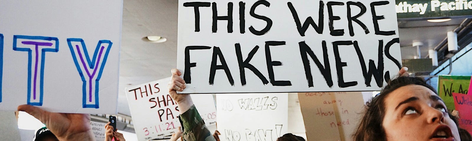 Photo of protesters with “I wish this were fake news” sign