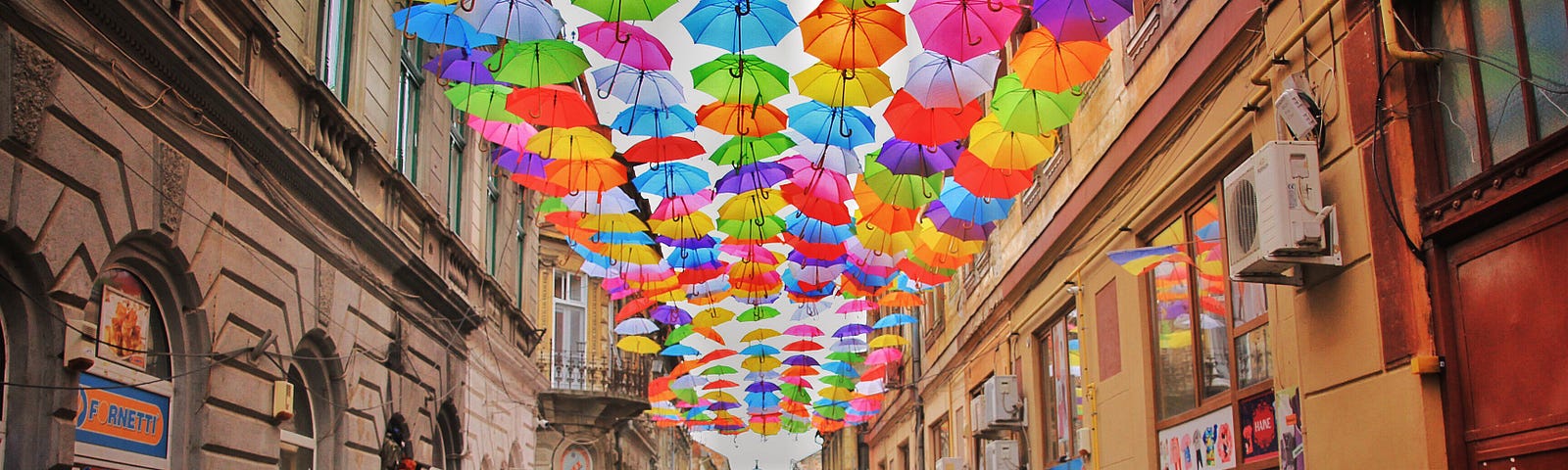 people walking down a street with colorful umbrellas above them