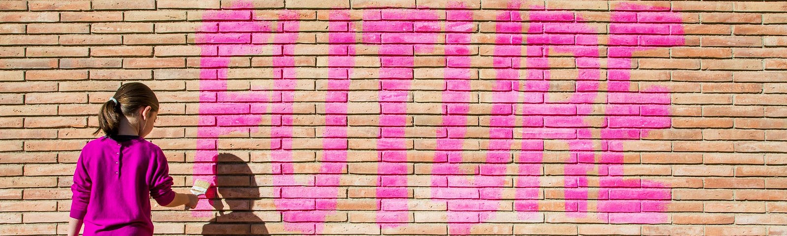 Young girl painting the word “Future” on a brick wall