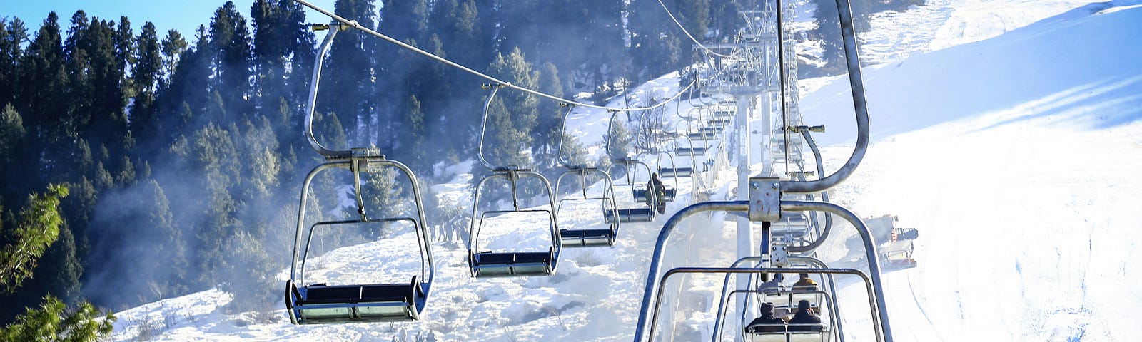 A chairlift going up and down a snowy mountain.