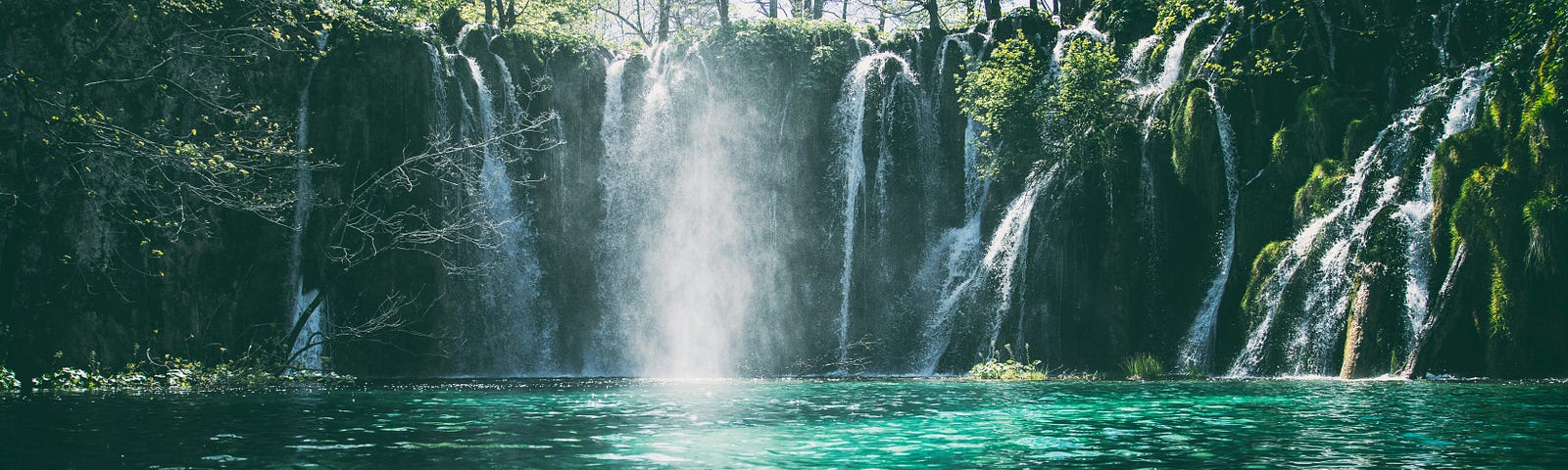 A waterfall at the end of a green-colored pond.