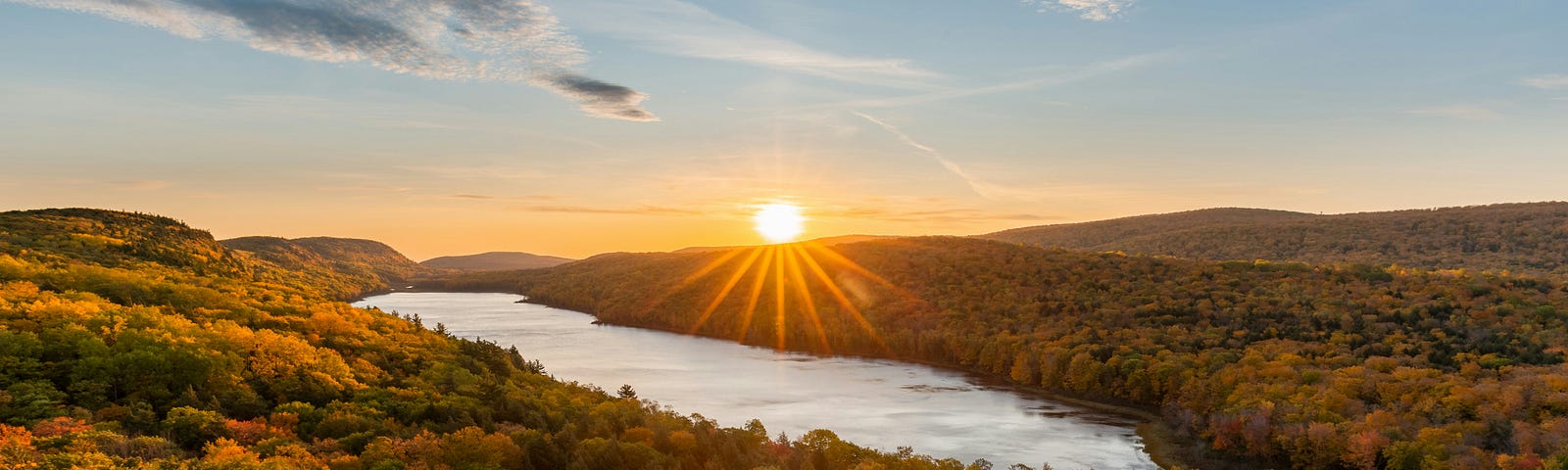 Golden sunrise over green landscape with a river running through.