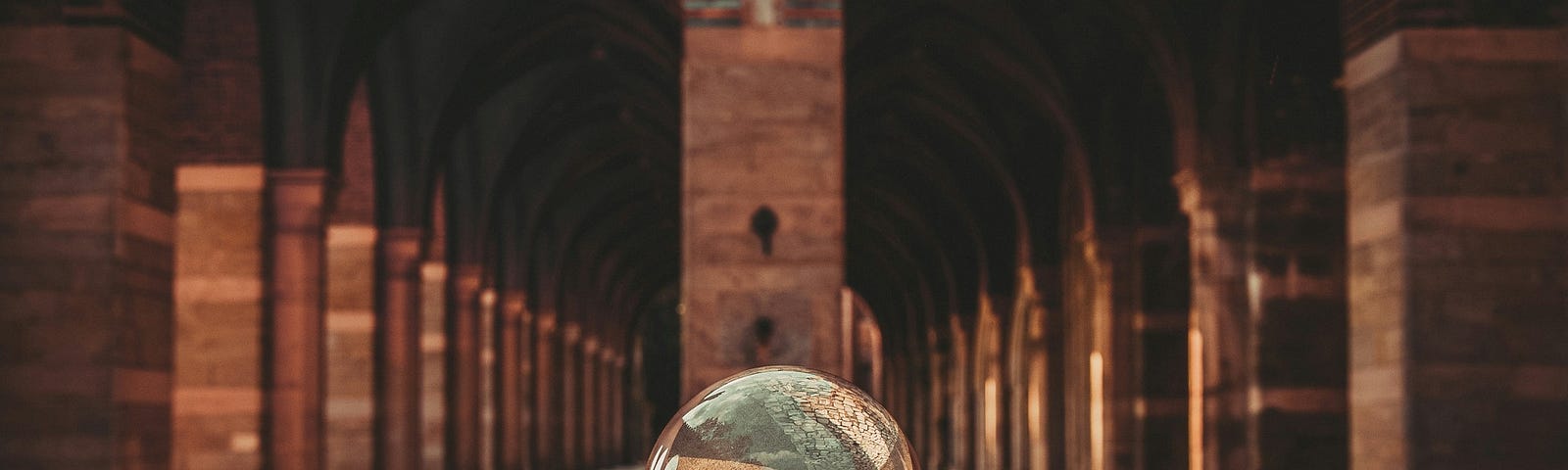 A hand with a glass sphere in the center. This shows the surroundings, a stone archway, upside down.