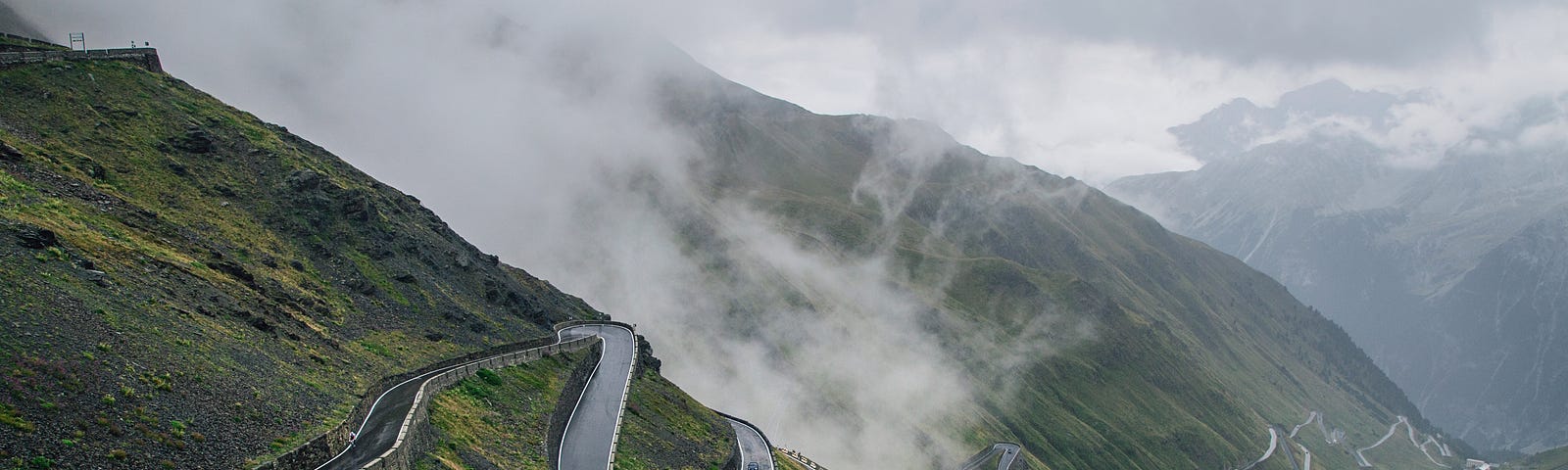 photograph of cars winding up a mountain road with a series of hairpin turns and switchbacks.