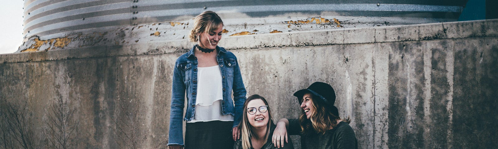 two girls are sitting and one girl is standing. They are possibly friends; picture to represent can you really have two best friends?