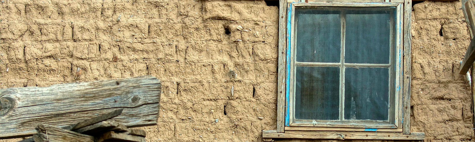 Picture of an old mud brick house with an old wooden, horse-driven cart