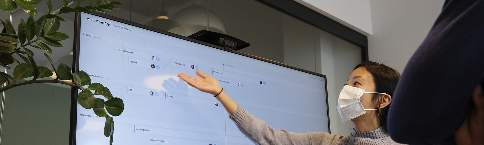 Masked teacher stands in front of TV screen