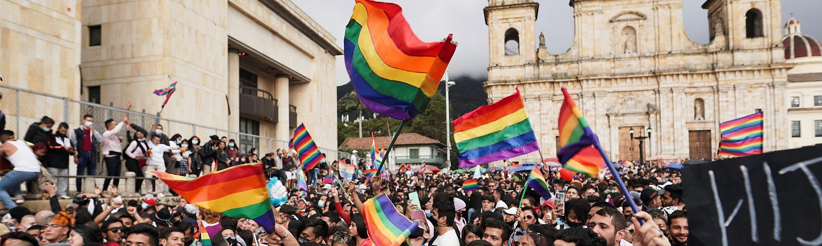 A crowd of people holding rainbow flags