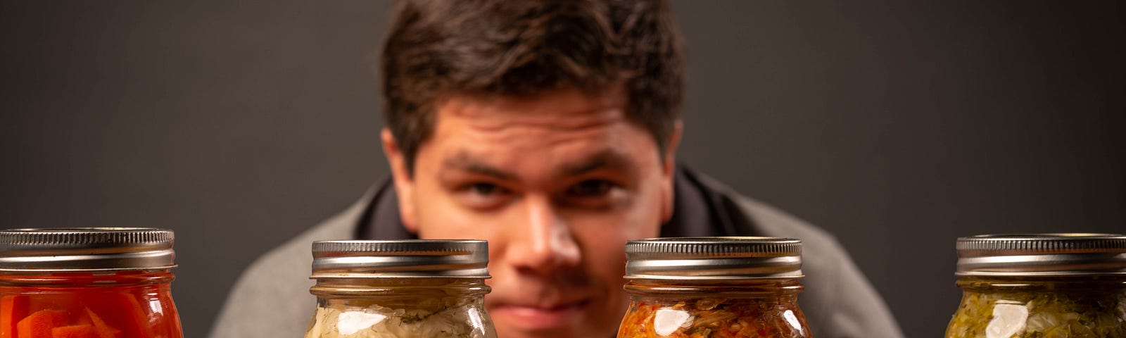 A man scrutinizing several jars of preserved food.