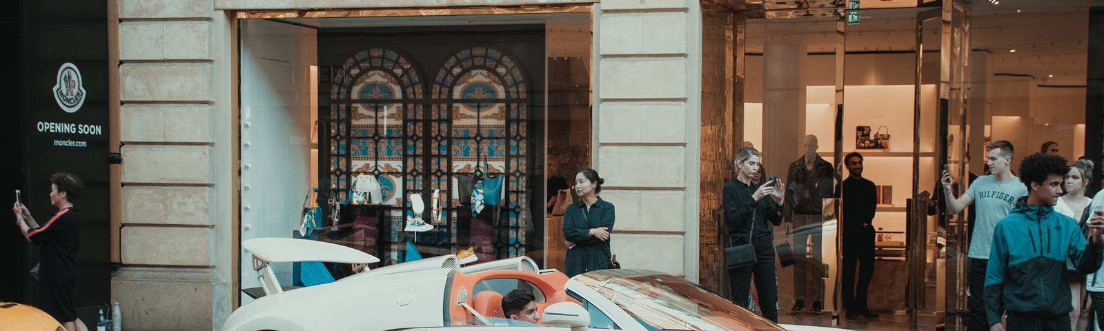 A white Chiron Pur Sport car in front of a white and gold colored Versace building