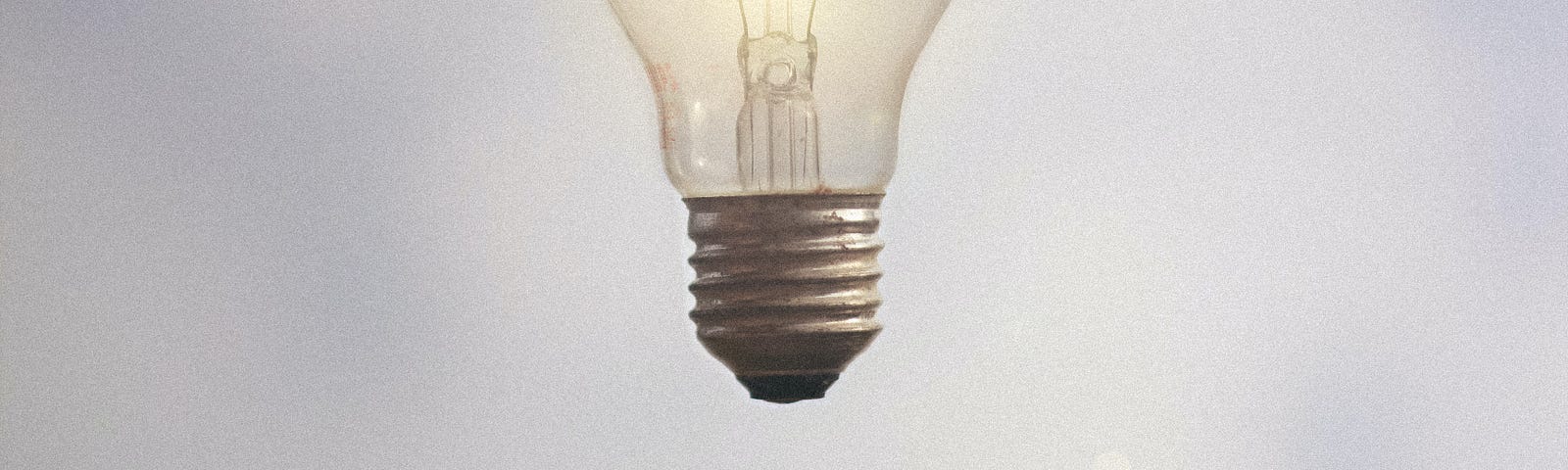 An electric bulb is suspended in the air with spread fingers under the bulb.