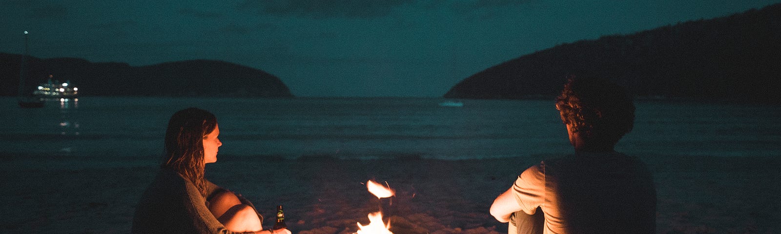 There Is a Fire — November Poem Competition — A Couple Sitting on the Beach with a Fire