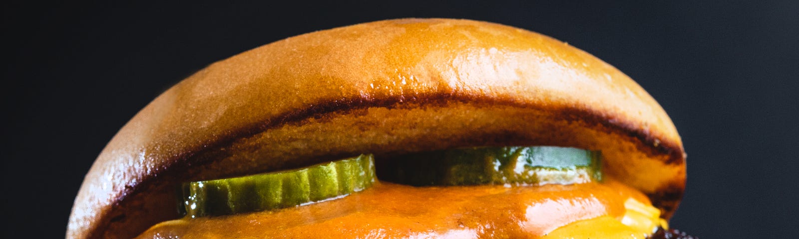 A big juicy hamburger with pickles, cheese, sauce and mustard