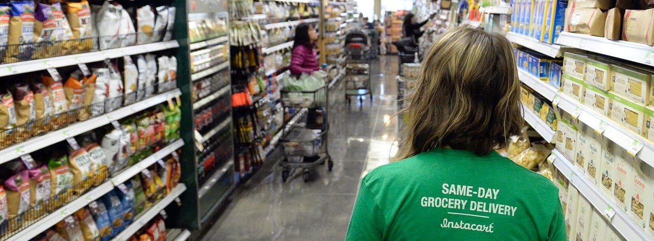 An Instacart employee walking down a food aisle.