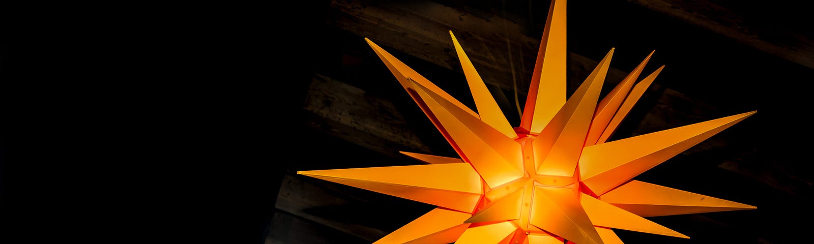Multi-dimensional bright orange pointed star offset against a black background.
