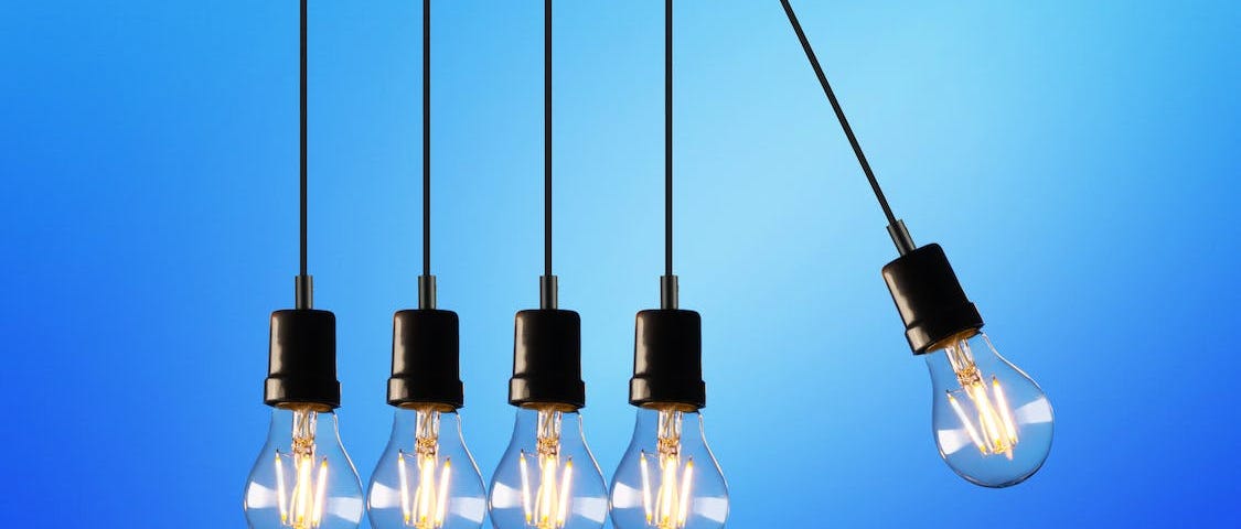 Five light bulbs: four hanging straight down, fifth one swinging away from the other four, as in Newton’s cradle.