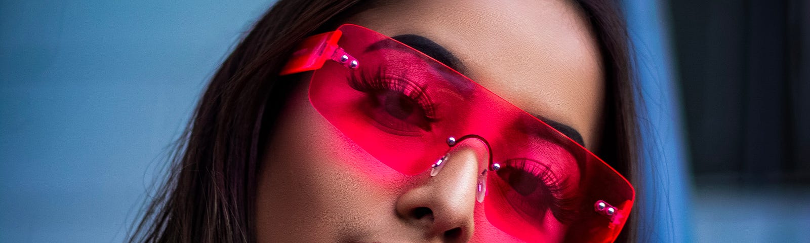 A young lady wearing glasses with neon pink-tinted lenses.