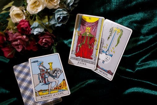 Four Tarot Cards on a rumpled tablecloth with flowers.