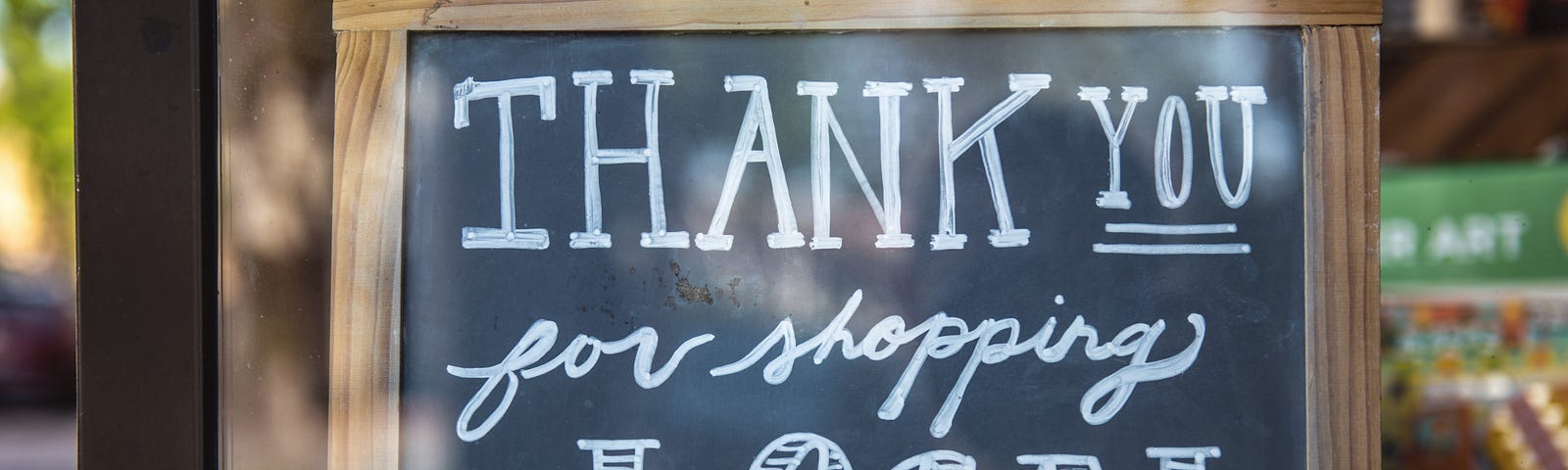 A small chalkboard with writing that says ‘Thank You for shopping Local’