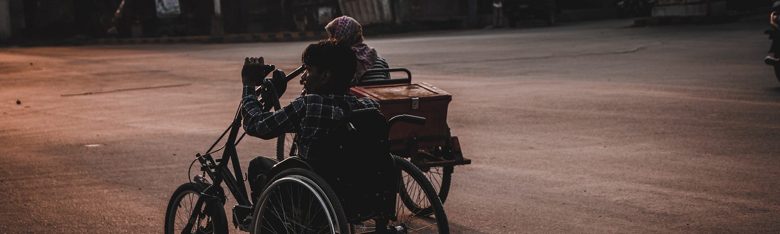 A disabled poor, south asian person going somewhere in  a handicapped tricycle.