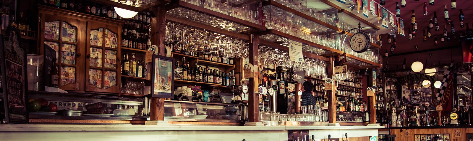 A picture of an old, wooden bar with an ornate back bar.