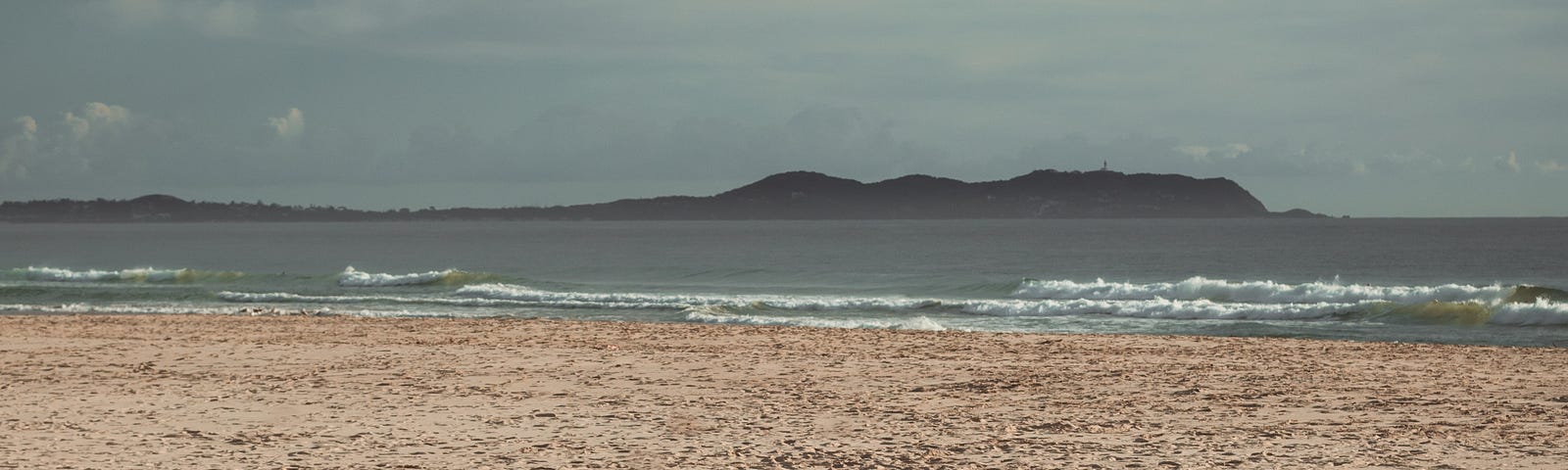 A woman sitting on the sand by the sea.