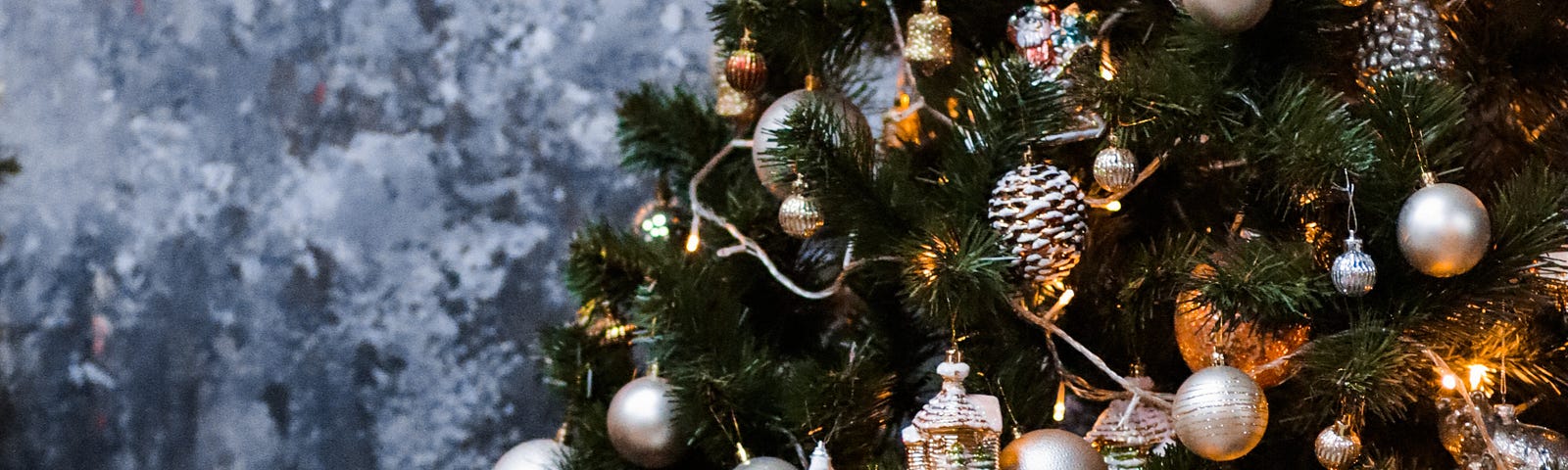 A decorated Christmas tree, dusted with fake frost and festooned with lights. Gifts are stacked haphazardly around its base.