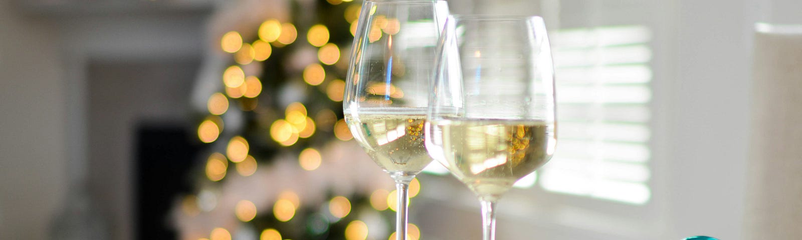 Two wine glasses on a table with Christmas baubles.