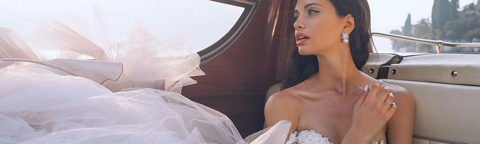 A beautiful bride inside a town car with the tule at the bottom of her dress all bunched up.