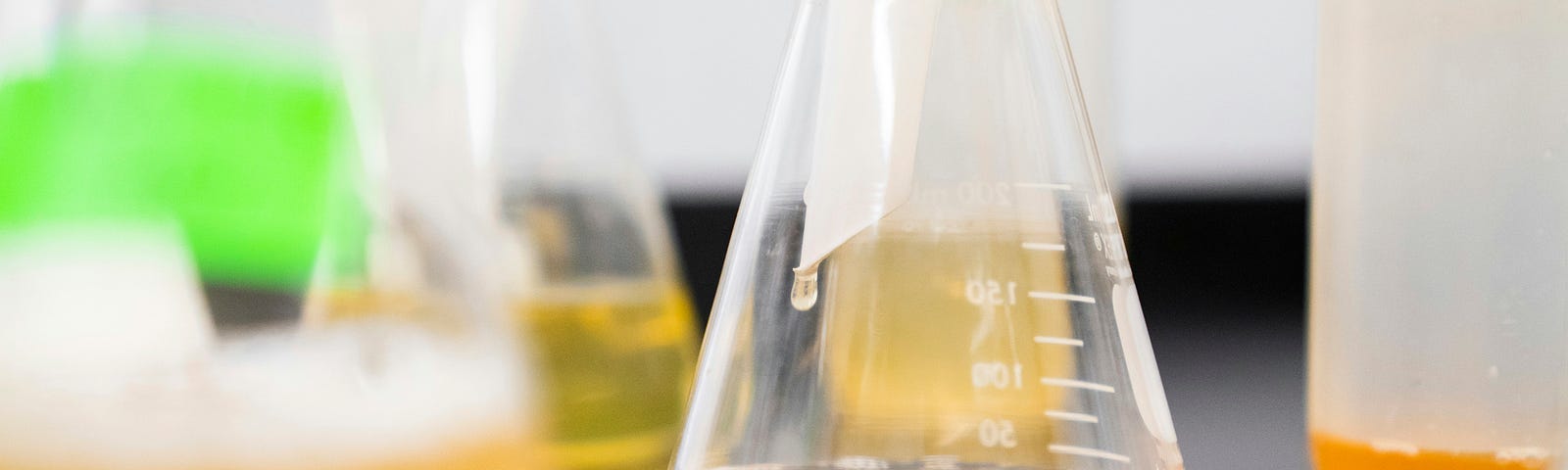 Vials full of orange liquid sit on a table in a lab.