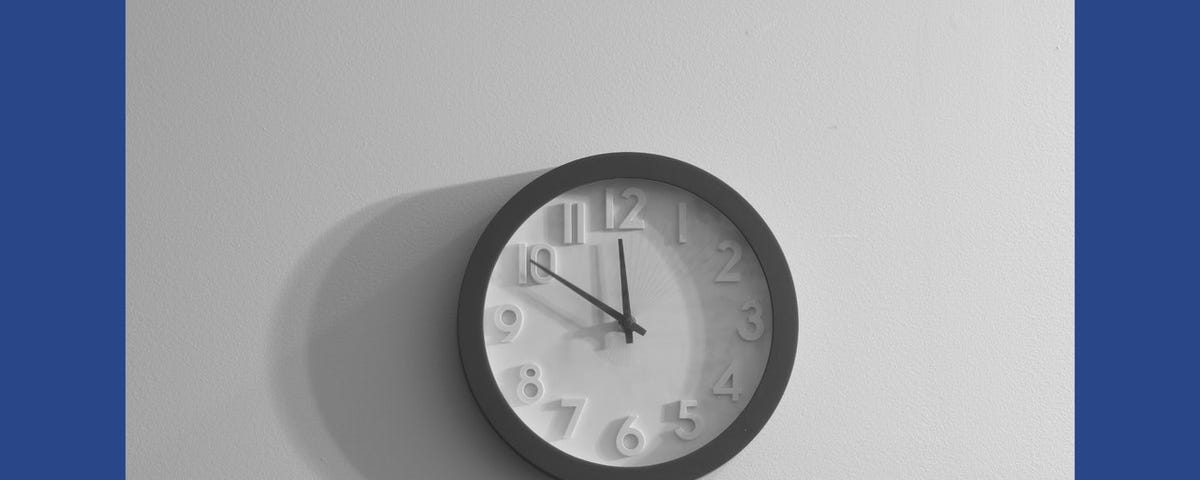 Image of a clock against a pale, grey wall.