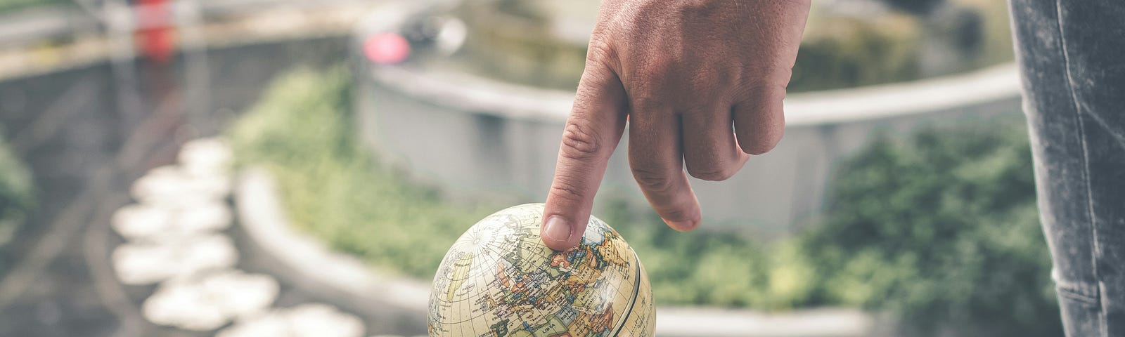 A finger points to an adventurous destination on a globe.