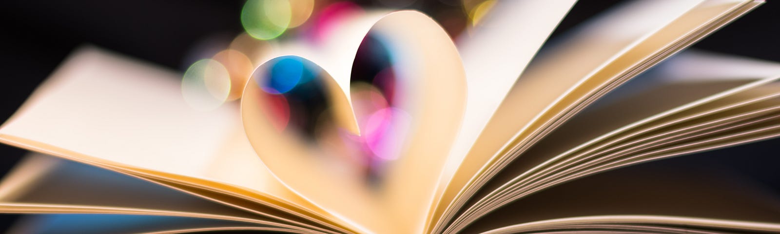 a paper book is open on desk with two pages folded together into spine to create a heart shape