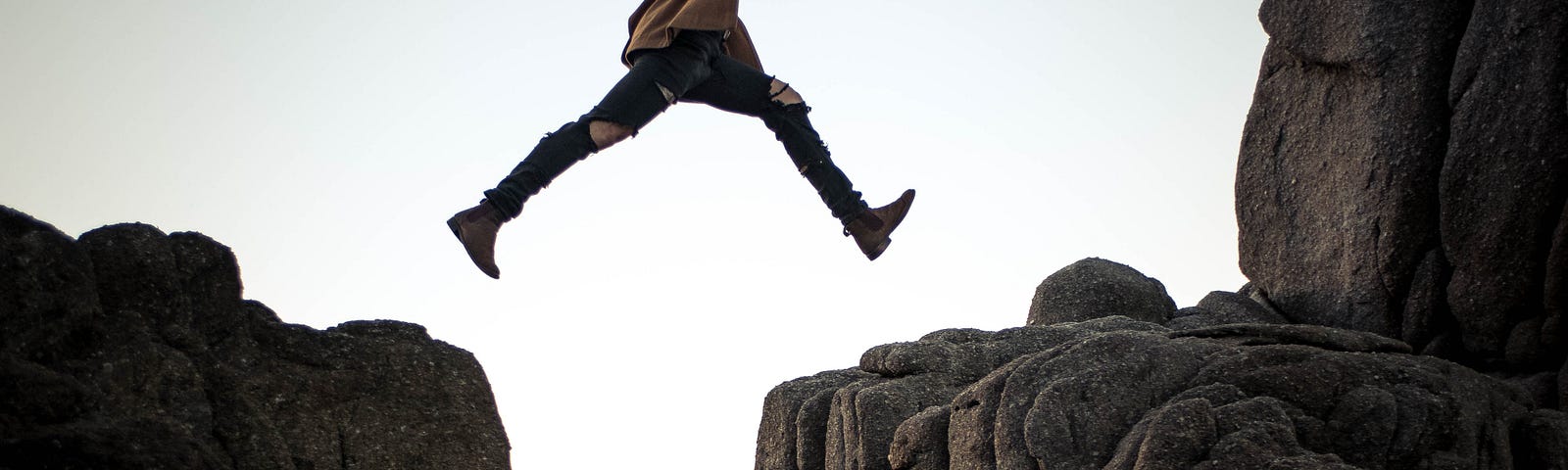 person leaping between two rocks